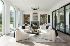 a living room filled with white furniture and a chandelier hanging from the ceiling