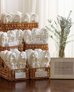 several baskets filled with white cloths on top of a wooden table next to a vase