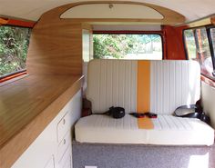 the interior of an rv with wood paneling and white seats, along with two windows