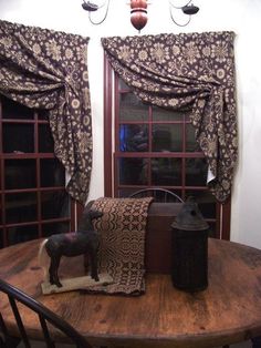 a wooden table topped with a brown and white horse figurine next to two windows