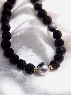 Adorned with a mix of textured lava beads and a single black Tahitian pearl, this handmade beaded necklace is a stylish personification of Hawaii’s enigmatic allure. This stunning Tahitian pearl necklace elegantly exemplifies mindful island living. Wear this for a classically elegant statement.✦ DETAILS ✦✧ Name: Roselani (rose-LAH-nee) - heavenly rose.✧ Adjustable Length from: 16"-18".✧ Genuine Tahitian Pearl 8-10mm AA-AAA quality; tone and shape varies.✧ 8mm Black Lava Beads✧ 14kt Gold Filled C Elegant Lava Stone Bracelets With Round Beads, Elegant Lava Stone Bracelet With Round Beads, Elegant Beaded Necklaces With Round Beads For Meditation, Elegant Round Beaded Necklaces For Meditation, Elegant Black Lava Stone Jewelry, Elegant Hand-strung Black Beaded Necklace, Elegant Hand-strung Black Necklace, Elegant Black Hand-strung Necklace, Hawaii Necklace