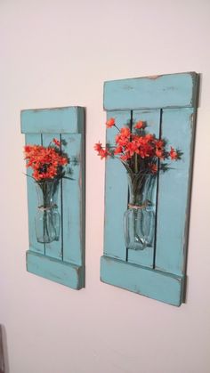 two vases with flowers in them are hanging on the wall