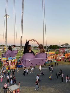 people are flying kites in the air at an amusement park with swings and rides