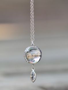 "A truly stunning, art deco era pools of light necklace. This one is made with an un-drilled rock crystal orb. It is bezeled in sterling silver with amazing floral detail. Orb measures 15mm around and connects to a marquise shaped channel set crystal. I love the detail to this one! The crystal is exceptional quality, with no major imperfections inside the jewel. Note how the crystal makes the images shining through flip upside down and backwards! Pendant hangs from sterling silver chain that is White Gold Art Deco Gemstone Necklace, Unique Drop Necklace With Large Pendant, Art Deco White Gold Round Necklaces, Unique Drop Gemstone Necklaces, Unique Faceted Necklaces, Art Deco White Gold Gemstone Necklace, Art Deco White Gold Necklace With Gemstone, Art Deco Crystal Jewelry For Gifts, Silver Round Art Deco Necklace