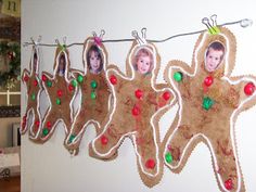 three gingerbread cutouts hanging from a line on a wall with christmas decorations around them