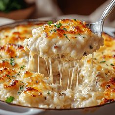 a spoon full of macaroni and cheese being lifted from a casserole dish