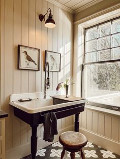 a black and white tiled floor in a bathroom with a sink, window, and stool