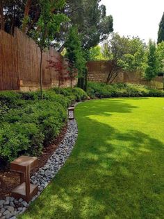 a garden with grass, rocks and trees in the back yard is well manicured