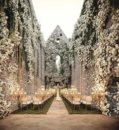 an outdoor wedding setup with white flowers and greenery on the walls, along with long tables