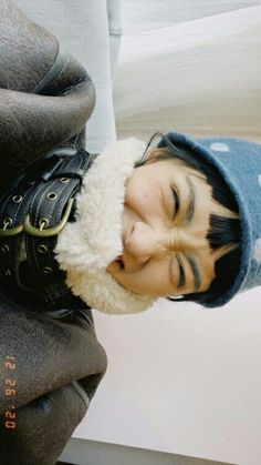 a young boy wearing a hat and holding his head up to the side with his mouth open