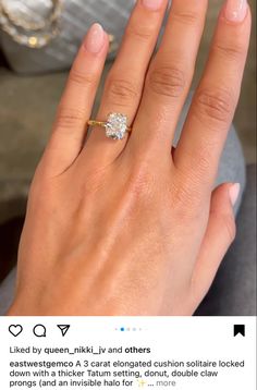 a woman's hand with a diamond ring on top of her finger and the other hand holding an engagement ring