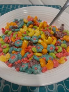 a white bowl filled with lots of different colored cereals on top of a table