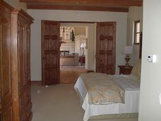 a bedroom with a bed, dressers and an open door leading to the kitchen