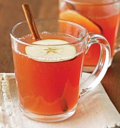 two mugs filled with apple cider and cinnamon sticks