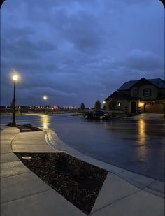 an empty street at night with cars parked in the parking lot