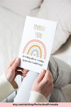 a woman holding up a card with the words thank you and a rainbow on it