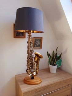 a lamp that is sitting on top of a dresser next to a vase with plants