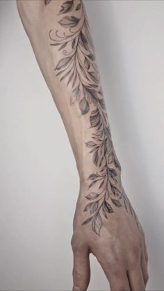 a person's arm with tattoos on it and leaves in the middle of their arm