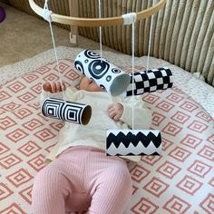 a baby laying on top of a bed next to a paper roll and some scissors