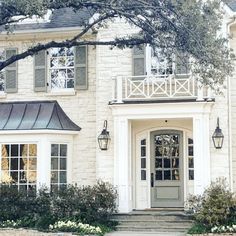 a large white brick house with two story windows and an iron roof over the front door