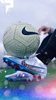 two soccer balls sitting on top of each other in front of a person's feet