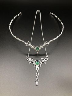 a silver necklace with green stones on it