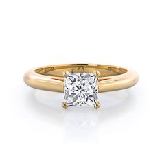 a yellow gold ring with a princess cut diamond in the center, on a white background