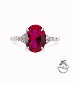 an oval ruby and diamond ring with two diamonds on the band, set in white gold