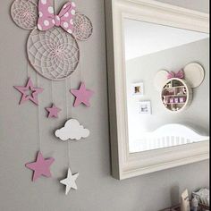 a pink and white minnie mouse mobile hangs on the wall next to a mirror in a girls'bedroom