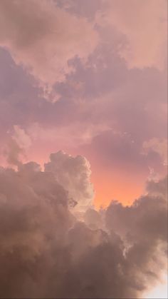 an airplane is flying through the clouds at sunset