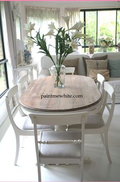 a vase with flowers sitting on top of a table in front of a couch and window