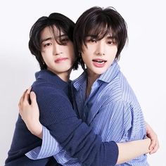 two young men hugging each other in front of a white background