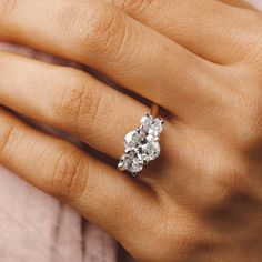 a woman's hand with a three stone diamond ring on her left and right hand