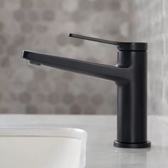 a black faucet sitting on top of a white counter next to a sink