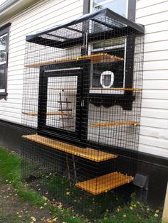 a bird cage sitting on the side of a house