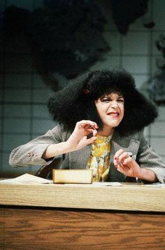 a woman sitting at a desk with an afro on her head