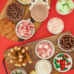 a wooden cutting board topped with bowls filled with candy and pretzels