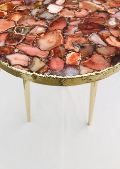 a small table with some kind of mosaic on it's surface and gold legs