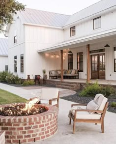 a fire pit sitting in the middle of a yard next to two chairs and a table