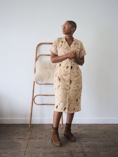 a woman standing in front of a chair with her arms crossed and looking up at the sky