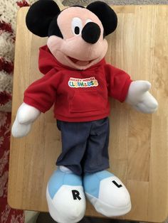 a mickey mouse stuffed animal sitting on top of a wooden table