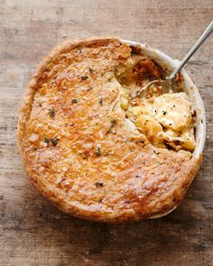 a pot pie with a serving spoon in it on a wooden counter top, ready to be eaten