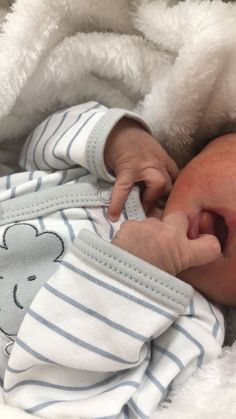 a baby is laying down with his hand on the head of someone's face