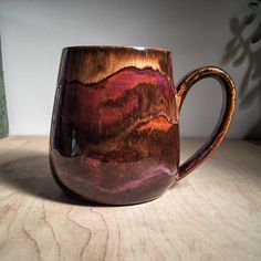 a coffee cup sitting on top of a wooden table next to a potted plant