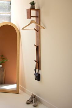 a pair of shoes is sitting on the floor next to a wall mounted coat rack