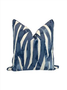 a blue and white pillow with zebra print on it's side, in front of a