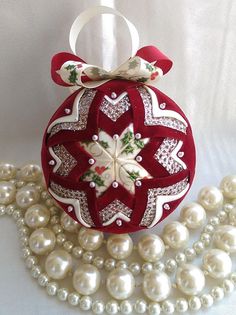 a red ornament sitting on top of a white table next to some pearls