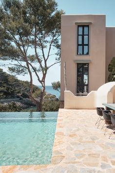 an outdoor dining area next to a swimming pool with chairs and table in the foreground