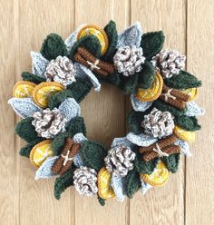 a crocheted wreath with leaves and flowers on a wooden surface in front of a door