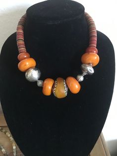 This is a mix of beads, amber, silver and african vinyl.  very pretty and ethnic.  it is a statement piece and goes with most everything.  measures 17.5" Unique Amber Beaded Necklace For Festival, Bohemian Orange Necklaces With Silver Beads, Amber Beaded Necklaces With Large Beads For Festival, Amber Beaded Necklace With Large Beads For Festival, Wood Bead Necklace, Unique Necklaces, Wood Beads, Amber, Silver Necklace